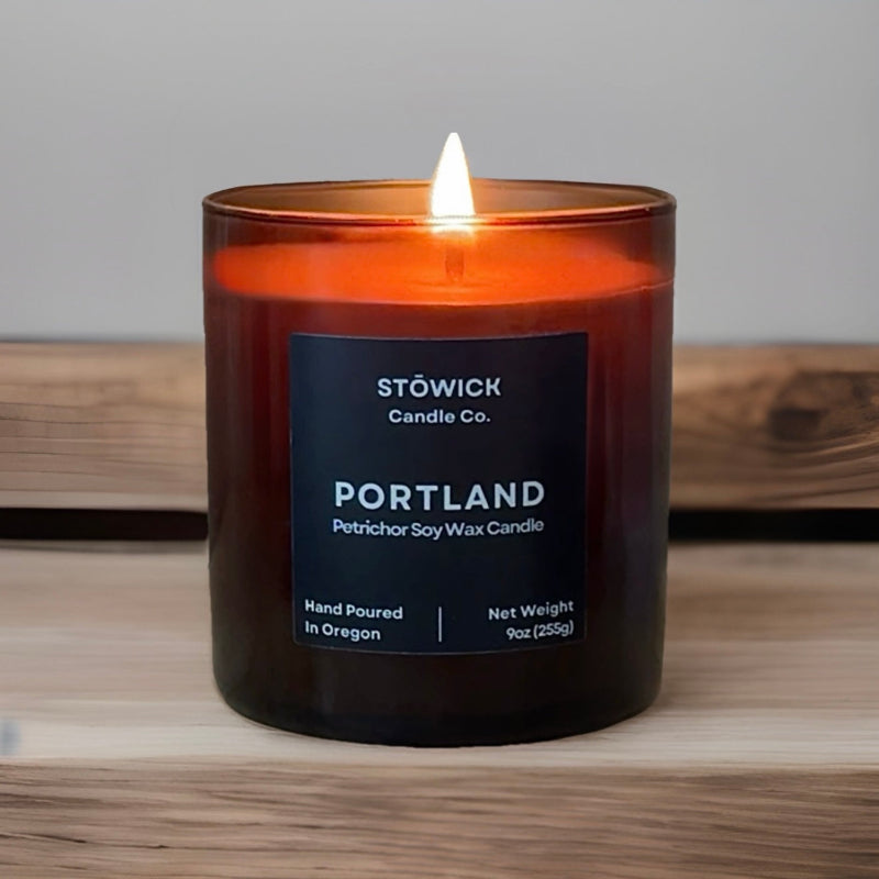 Lit portland tumbler candle with a label on a wooden surface