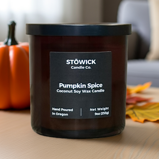 Stöwick Pumpkin Spice candle on a table with a pumpkin and leaves in the background