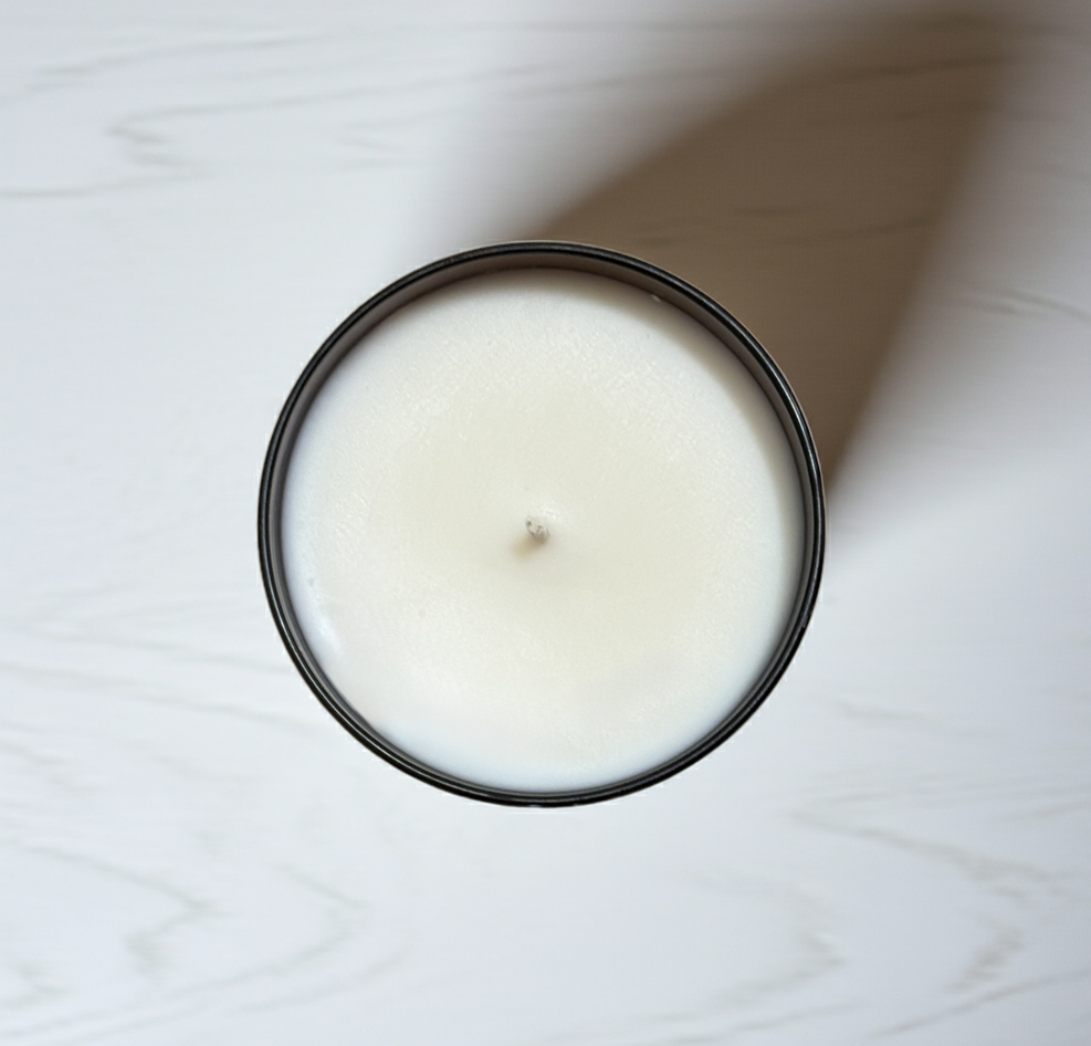 White candle in a black container on a white surface with roasted chestnut fragrance