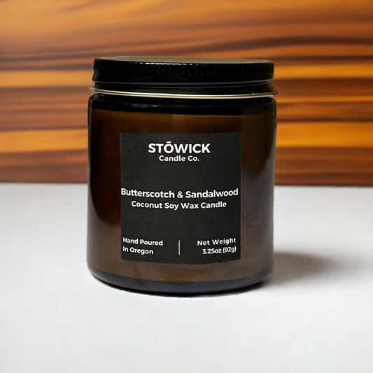 butterscotch and sandalwood mini candle in an amber jar sitting on a table