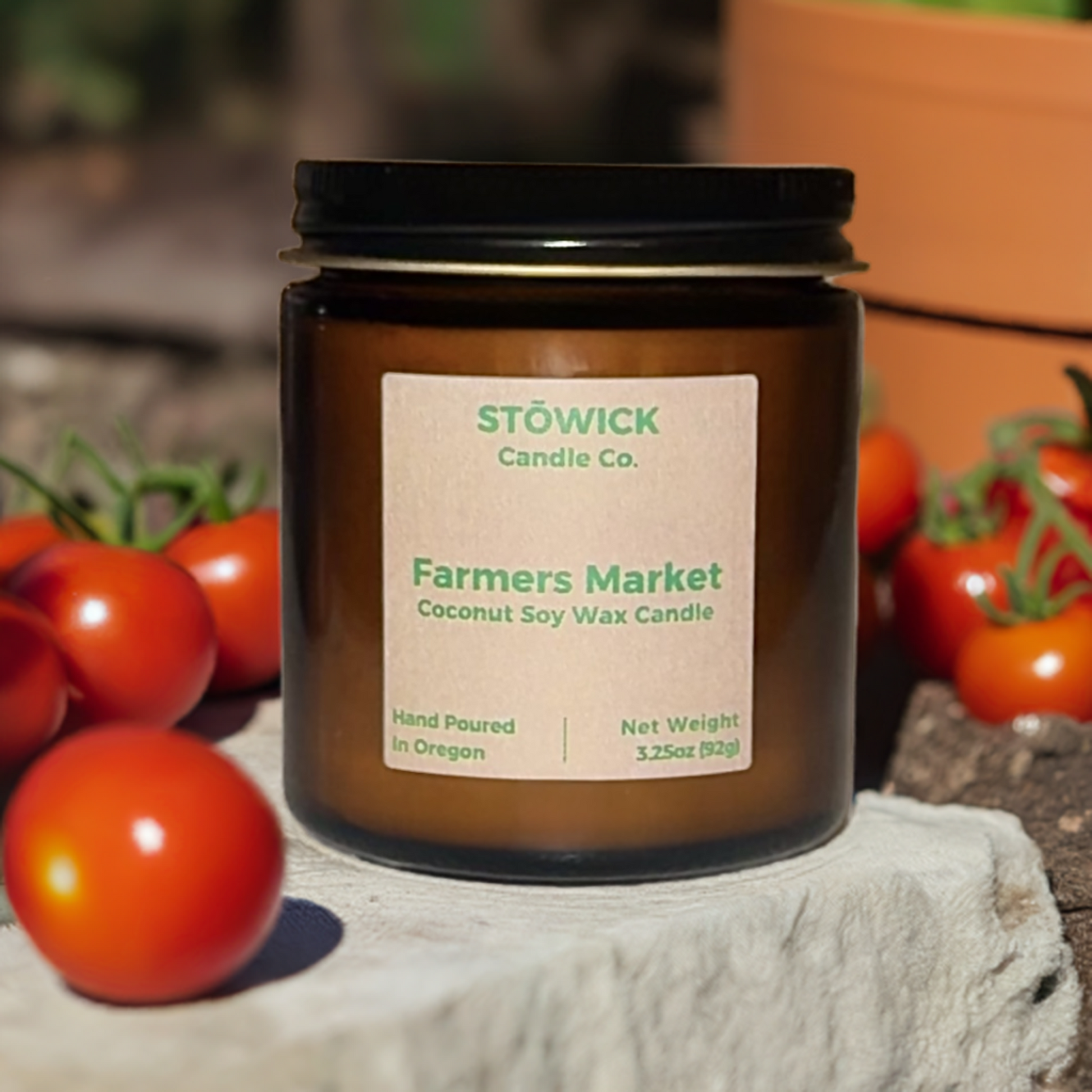 farmers market mini candle sitting outside in a garden surrounded by red tomatoes
