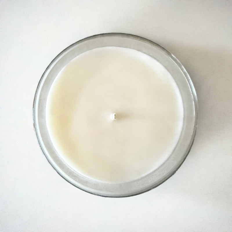 A Birds Eye view of a grapefruit candle made from soy coconut wax. The wax is white and in a clear glass jar. The background is white.