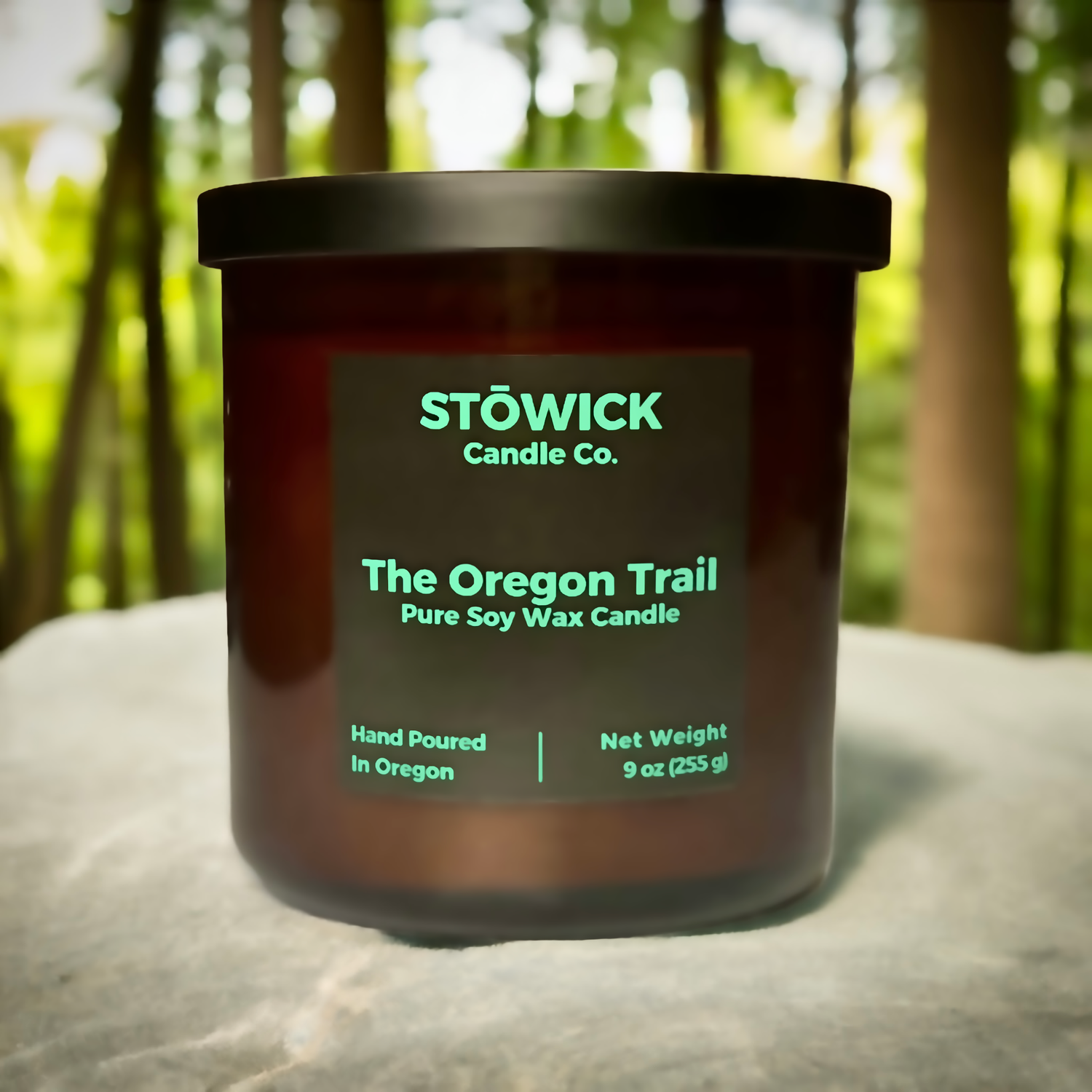 A soy wax candle sitting on a rock outside with the fragrance the Oregon trail made by Stowick 