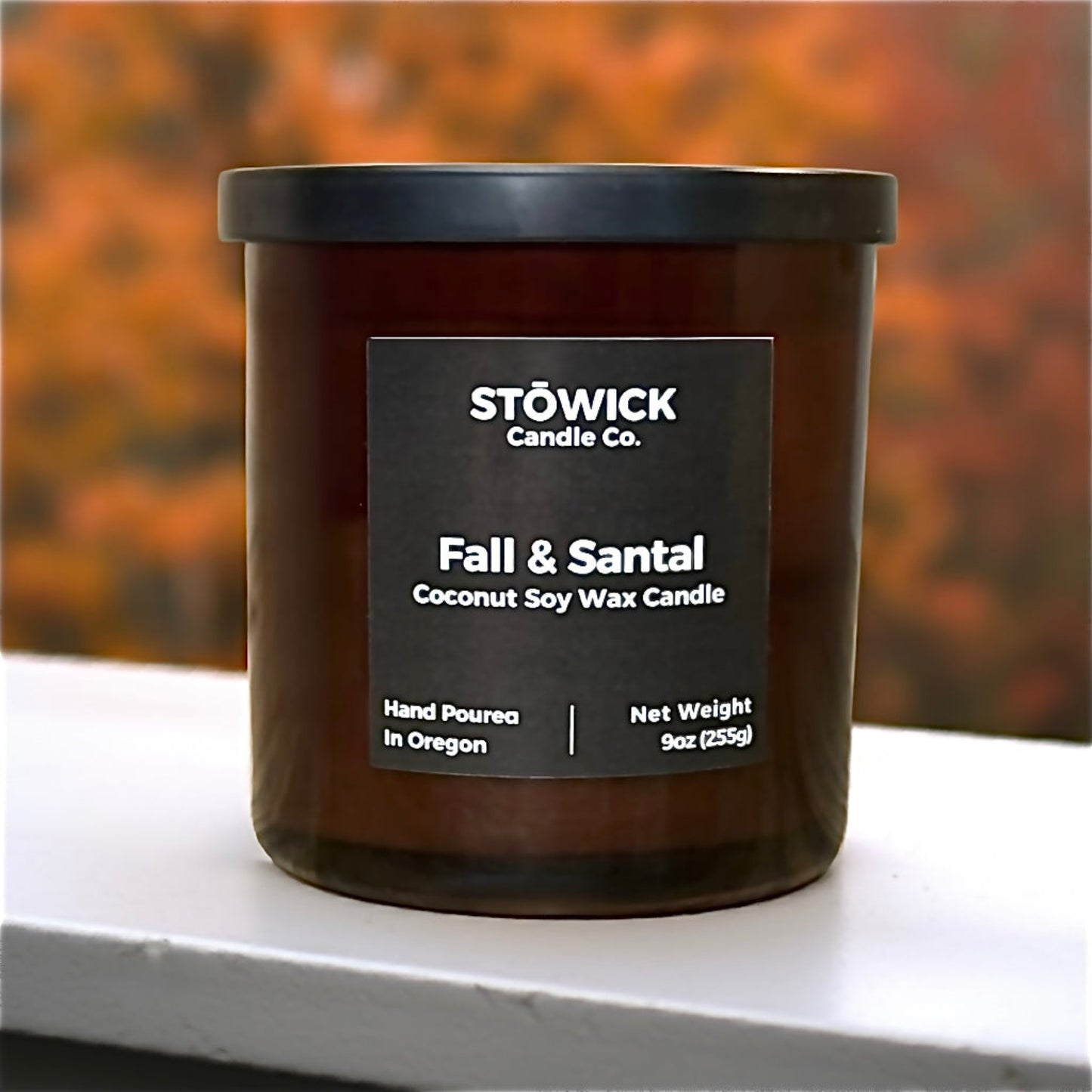 Fall And Santal Tumbler Candle sitting on a railing