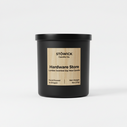 A hardware store lumber scented candle in a black jar with a white background 
