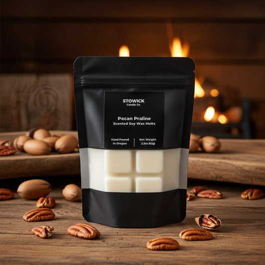 Pack of Stowick Candle Co. Pecan Praline scented wax melts on a wooden surface with pecans and a fireplace in the background.