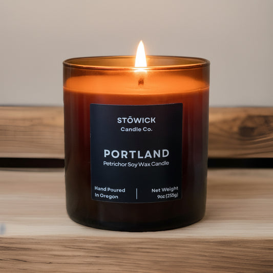 Lit portland tumbler candle with a label on a wooden surface