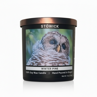 A winter pine scented tumbler candle with a barred owl on the front