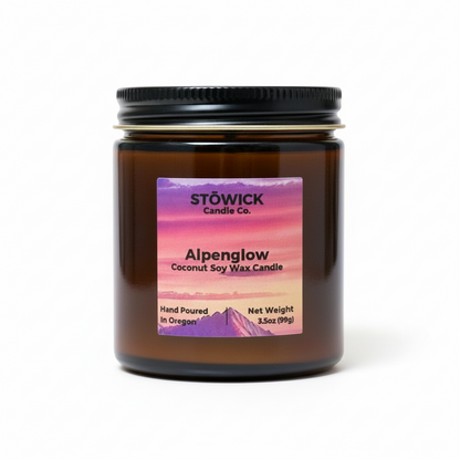An alpenglow scented mini candle with an alpenglow label on an amber jar