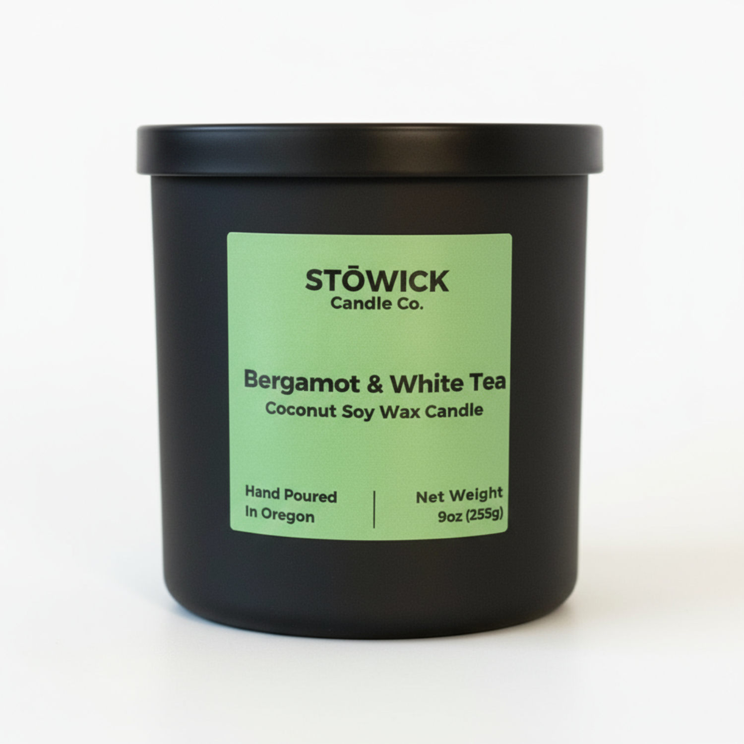 Black candle jar with a green label featuring Stowick Candle Co. on a white background with the fragrance bergamot and white tea 
