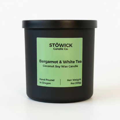 Black candle jar with a green label featuring Stowick Candle Co. on a white background with the fragrance bergamot and white tea 