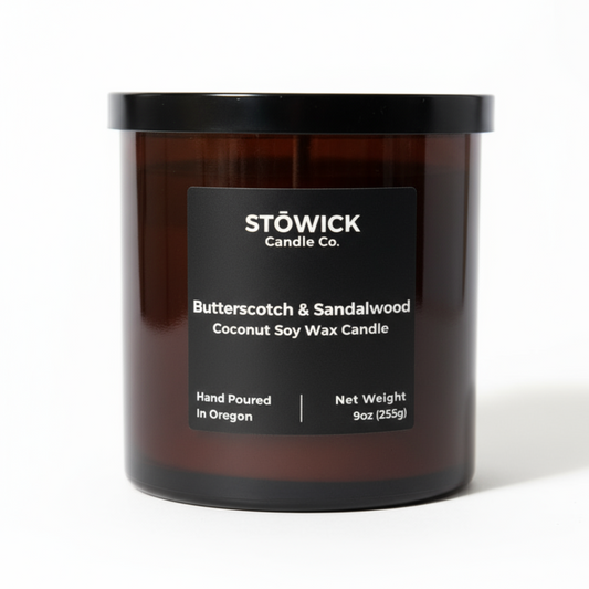 A butterscotch and sandalwood scented candle in a brown glass jar with a black label 