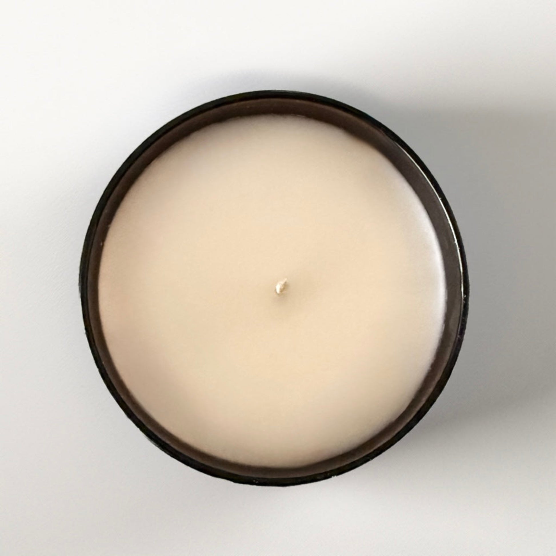 A bird’s eye view of a butterscotch sandalwood candle in an amber jar with white wax