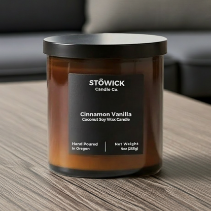 Stowick Candle Co. cinnamon vanilla tumbler candle on a wooden table with a blurred sofa in the background