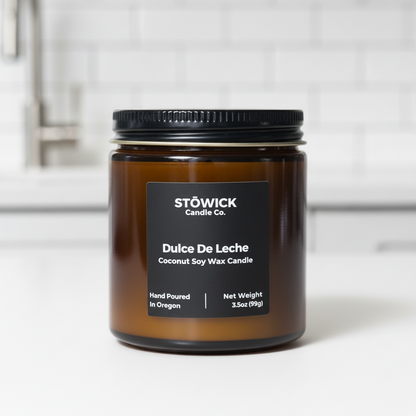 A dulce de leche mini candle in an amber jar with a black label on a white background 