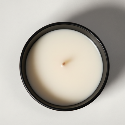 White candle in a black container on a light gray background