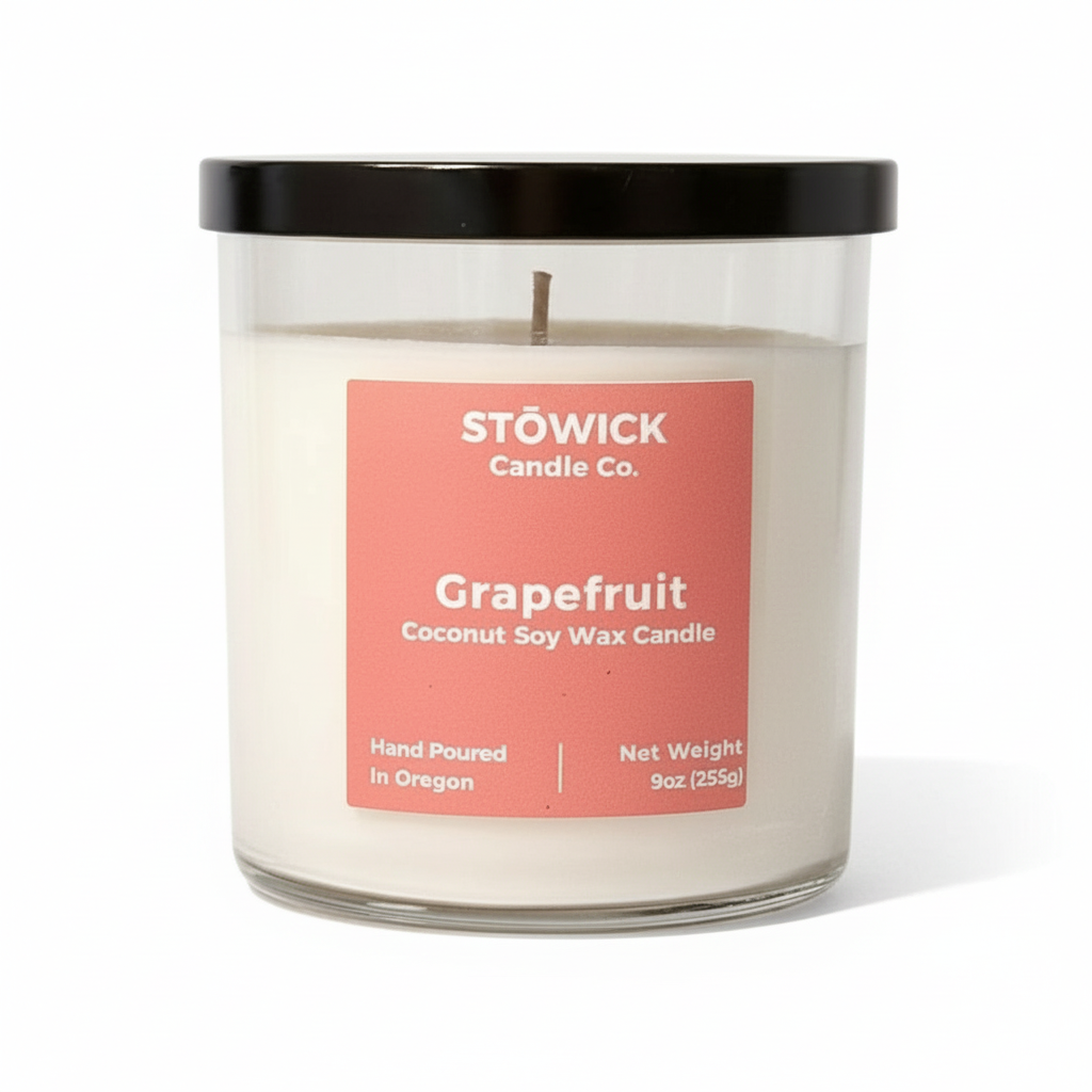 A grapefruit scented tumbler candle in a glass jar with a peach colored label