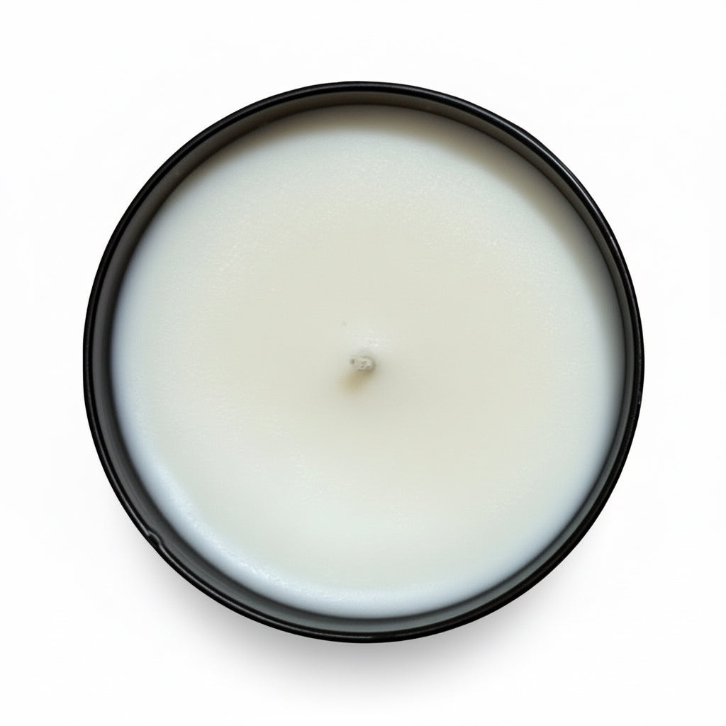 A hardware store tumbler candle with white wax in a black jar view from above on a white background 