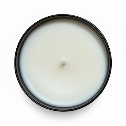 A hardware store tumbler candle with white wax in a black jar view from above on a white background 