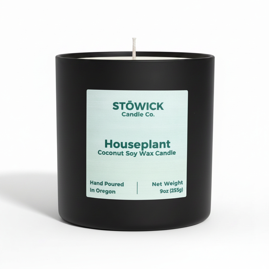A house plant scented tumbler candle in a black jar with the lid off on a white background