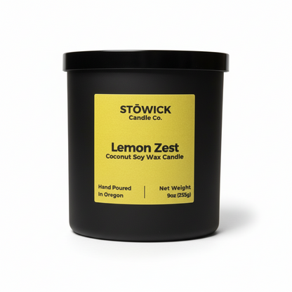 A lemon zest scented tumbler candle in a black jar with a yellow label