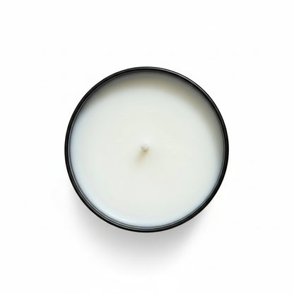 White candle in a black container on a white surface 