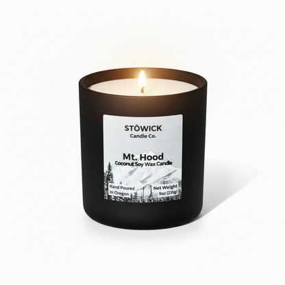 A lit mt hood tumbler candle with alpine scent against a white background 
