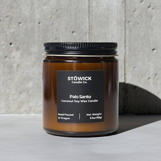 Stowick Candle Co. Palo Santo mini candle in a brown jar with black lid on a gray surface.