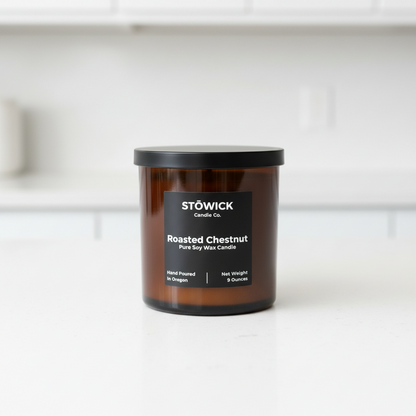 A roasted chestnut candle in an amber jar on a white counter