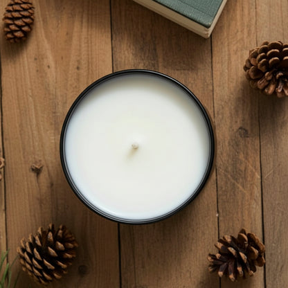 Spiced apple tumbler candle in an amber jar on a wooden surface with pine cones