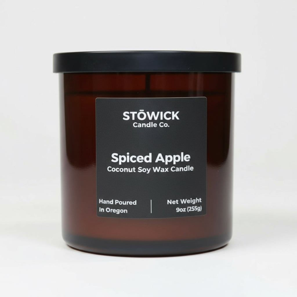 A spiced apple scented tumbler candle in an amber jar with a white background
