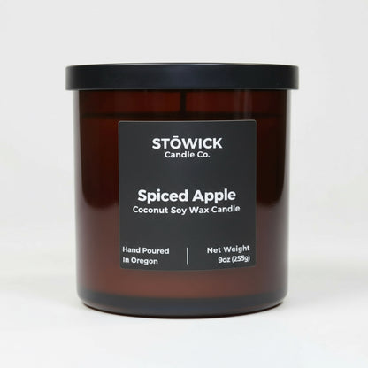 A spiced apple scented tumbler candle in an amber jar with a white background