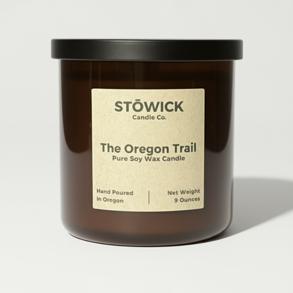 An Oregon trail tumbler candle in and amber jar against a white background 