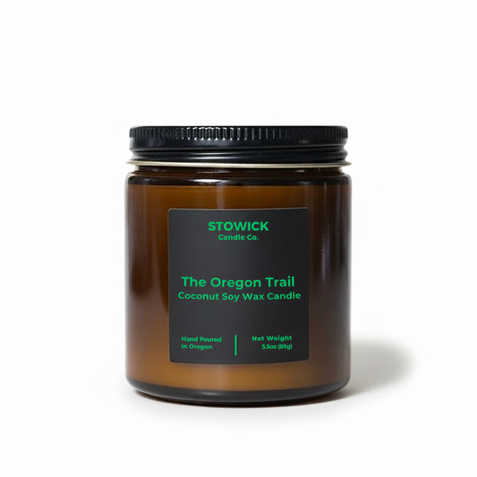The Oregon trail mini candle in an amber jar with a black label on a white background
